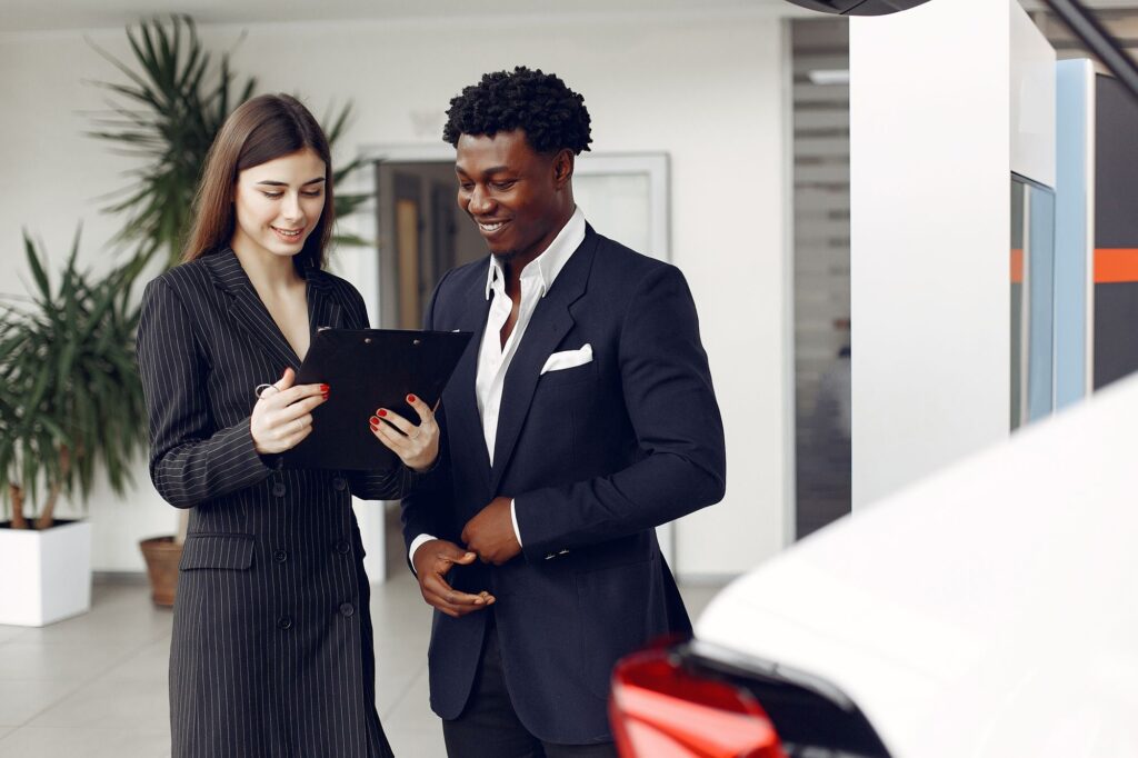 Car dealer and client reviewing a document together