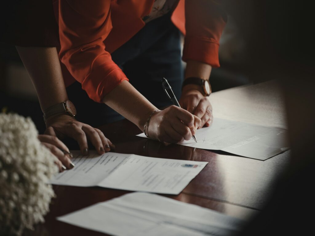 Person signing contract paperwork at a table