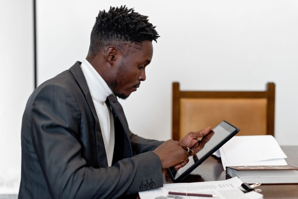 F&I manager using a tablet at a desk next to paper contracts